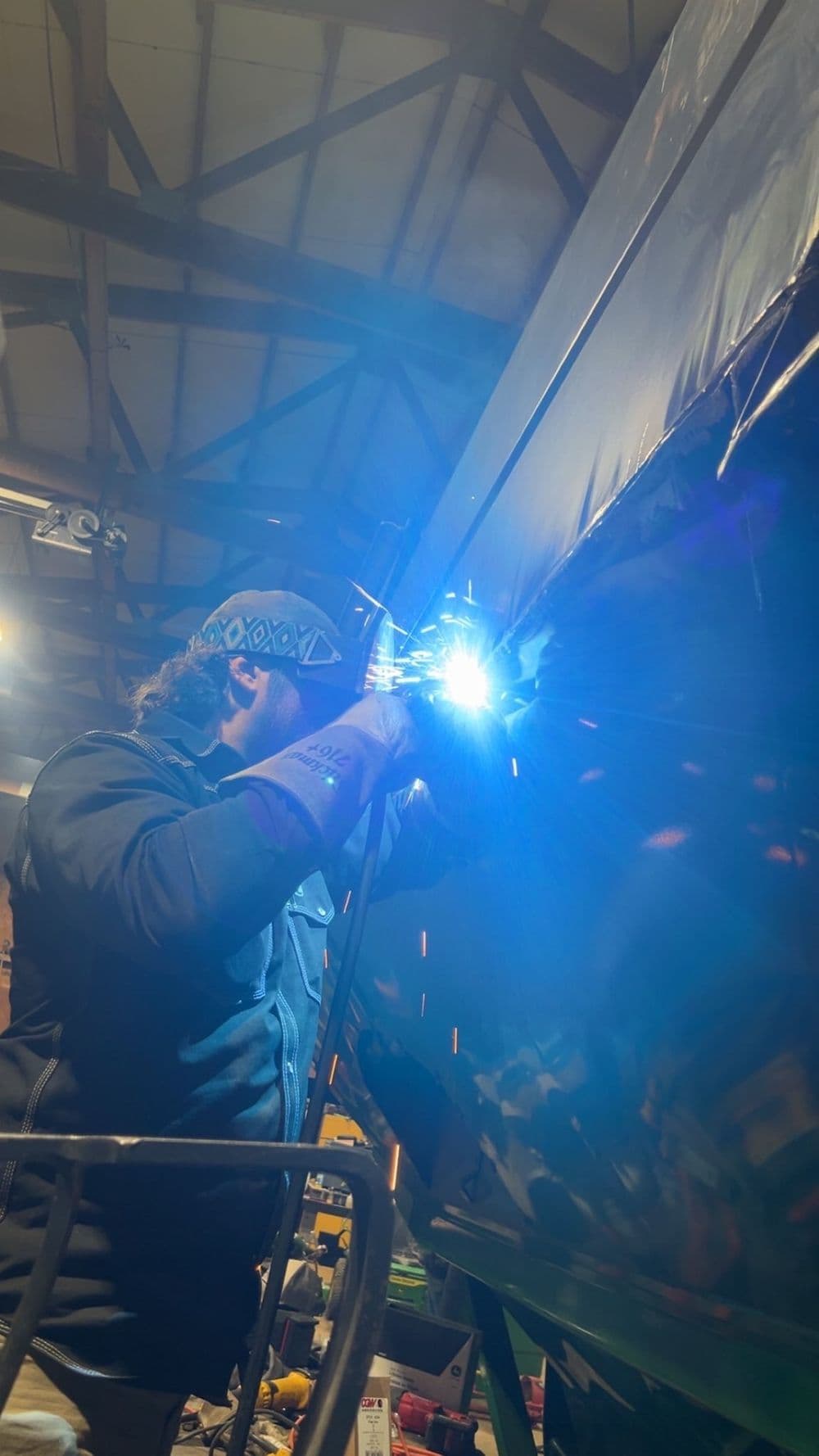 Welder creating sparks while working on metal in a workshop setting.