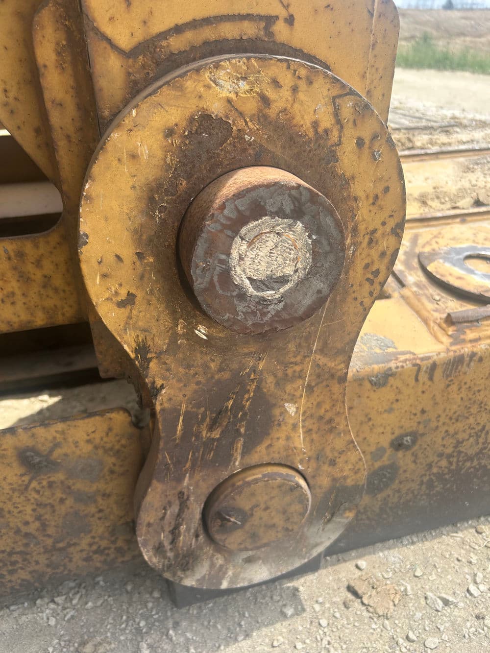 Close-up of a rusted hydraulic bolt on heavy machinery, showcasing wear and tear.