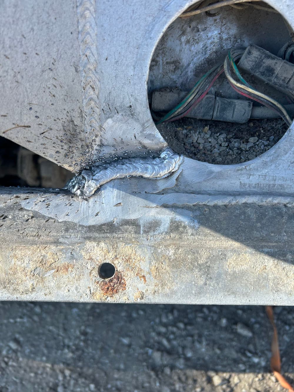 Close-up of metal weld on machinery part highlighting repair details and wiring connections.